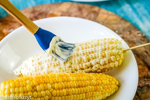 brushing butter on corn on the cob