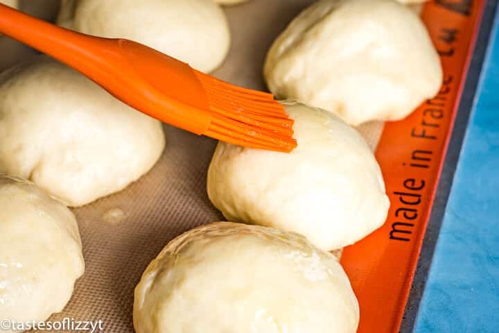brushing butter on dough balls