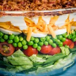 closeup of seven layer salad in a glass bowl