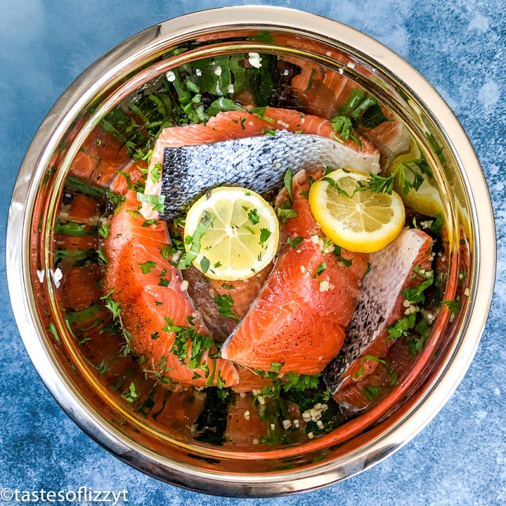 salmon marinating in a bowl with lemons