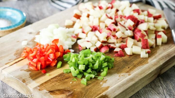 Food on a wooden cutting board, with Potatoes and peppers