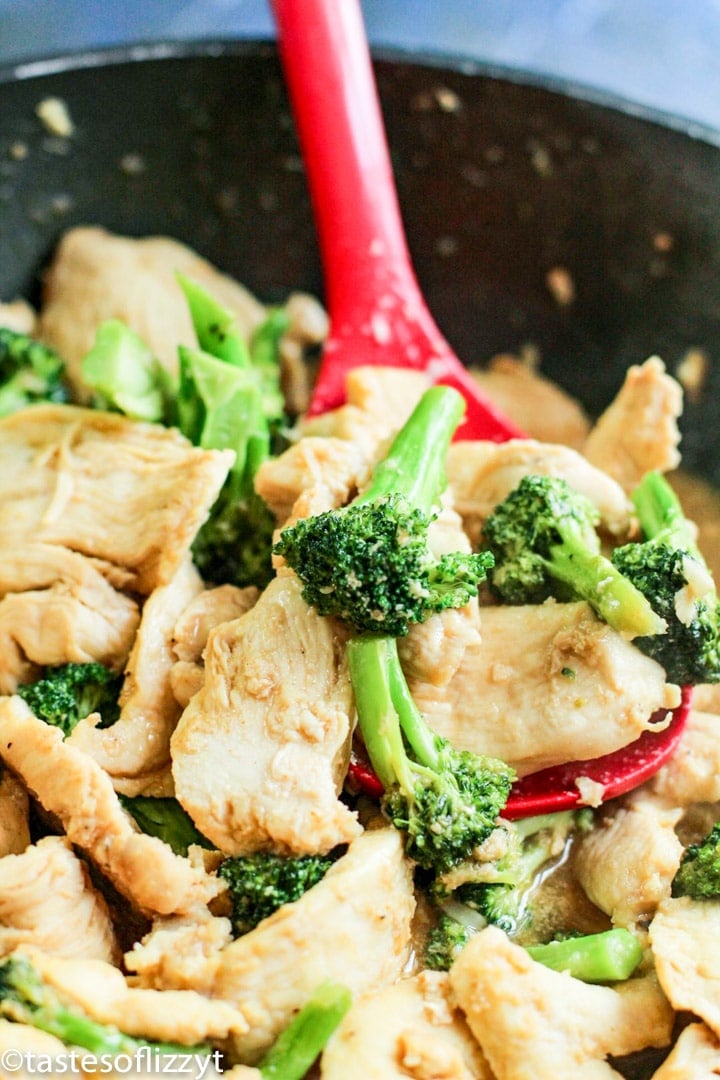 A close up of a bowl of food with broccoli, with Chicken on a spoon