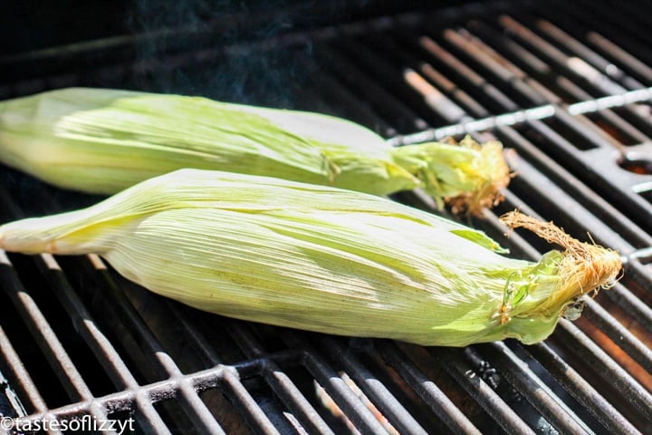 A close up of food on a grill, with Husk and Corn on the cob