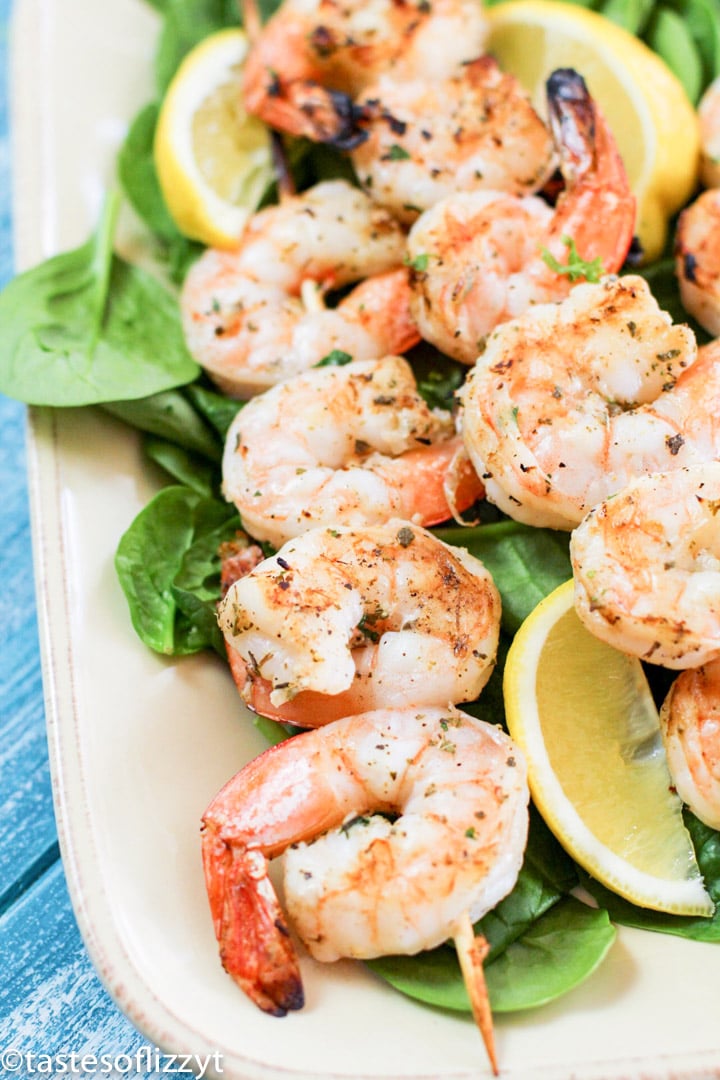 A plate of shrimp and vegetables, with Lemon and Skewer