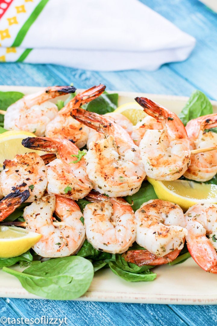 A plate of shrimp and vegetables, with Lemon and Skewer