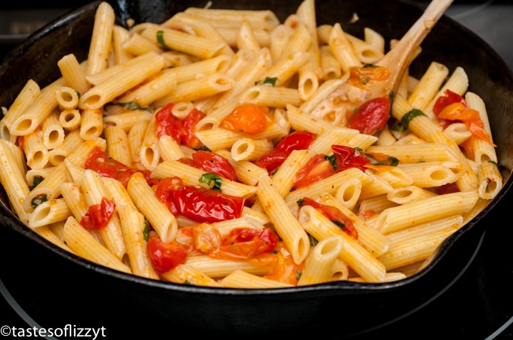 A bowl filled with pasta and vegetables, with Tomato and Basil
