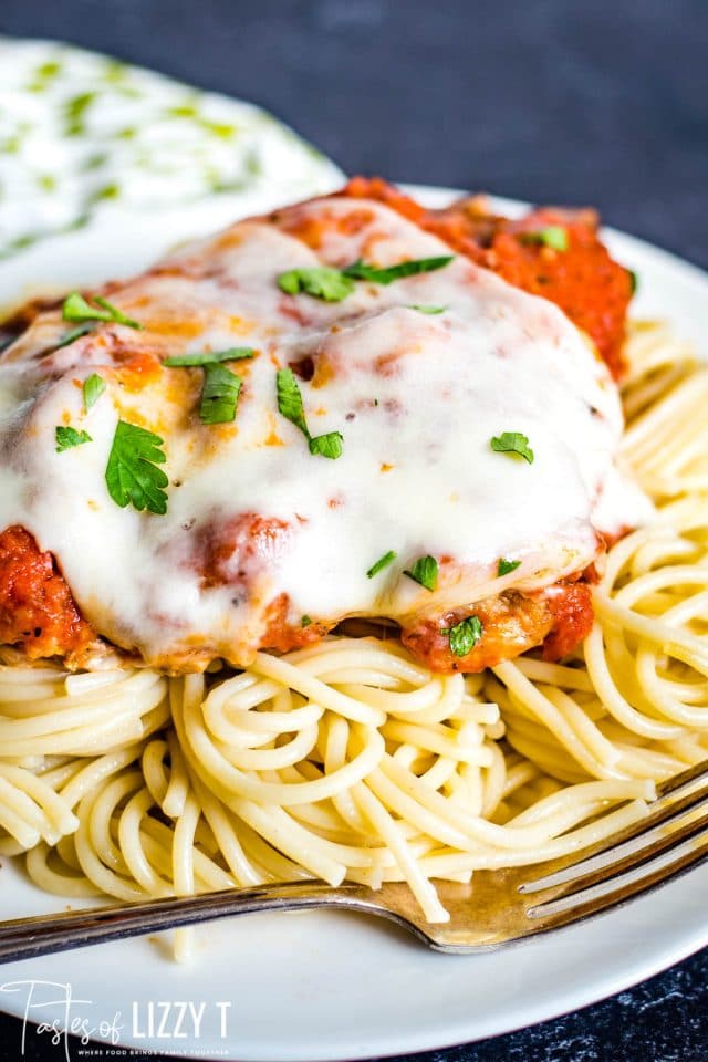 A close up of a plate of cube steak and pasta with sauce and cheese