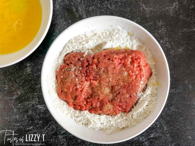 cube steak in a bowl of flour