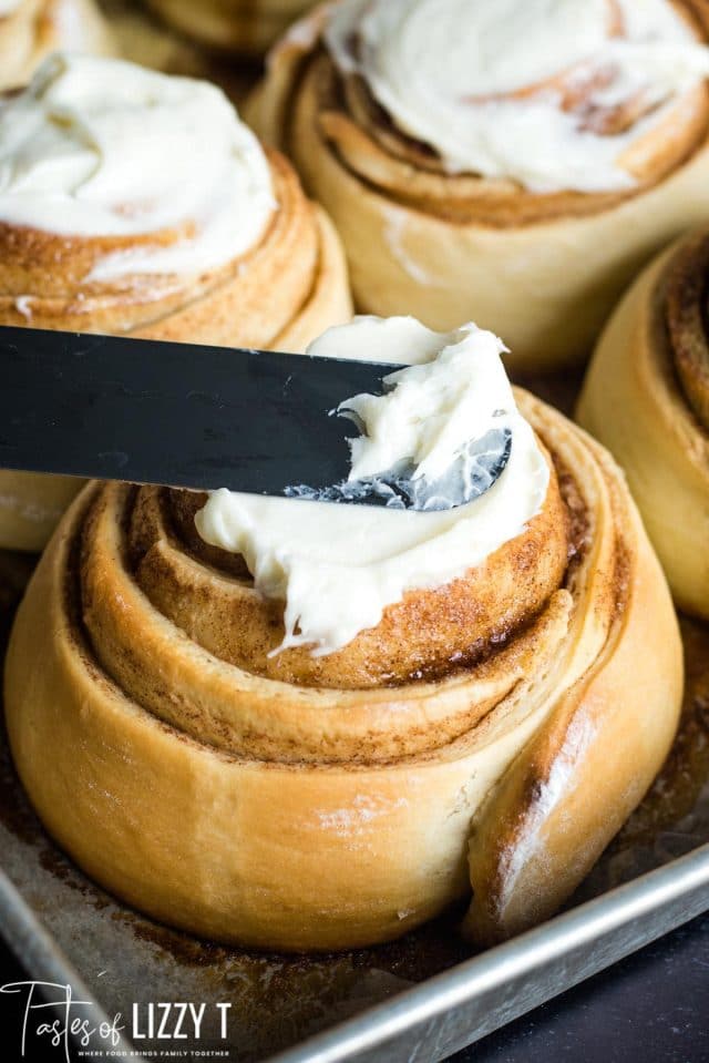 spreading frosting on a cinnamon roll
