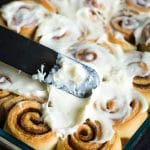 spreading cream cheese frosting on cinnamon rolls