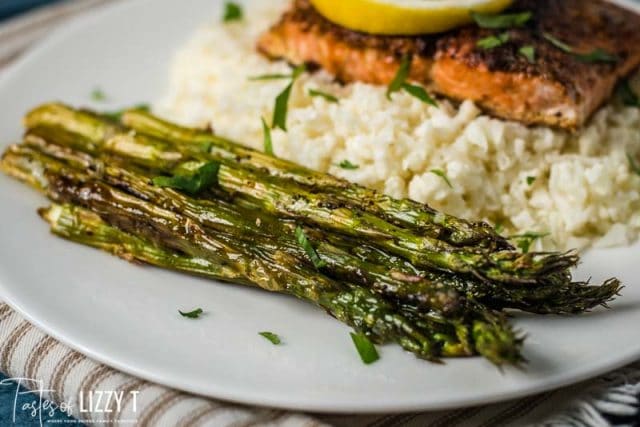 A plate of food with asparagus, rice and salmon