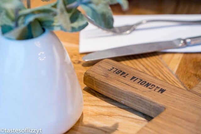 A knife sitting on top of a wooden cutting board, with Waco and Family