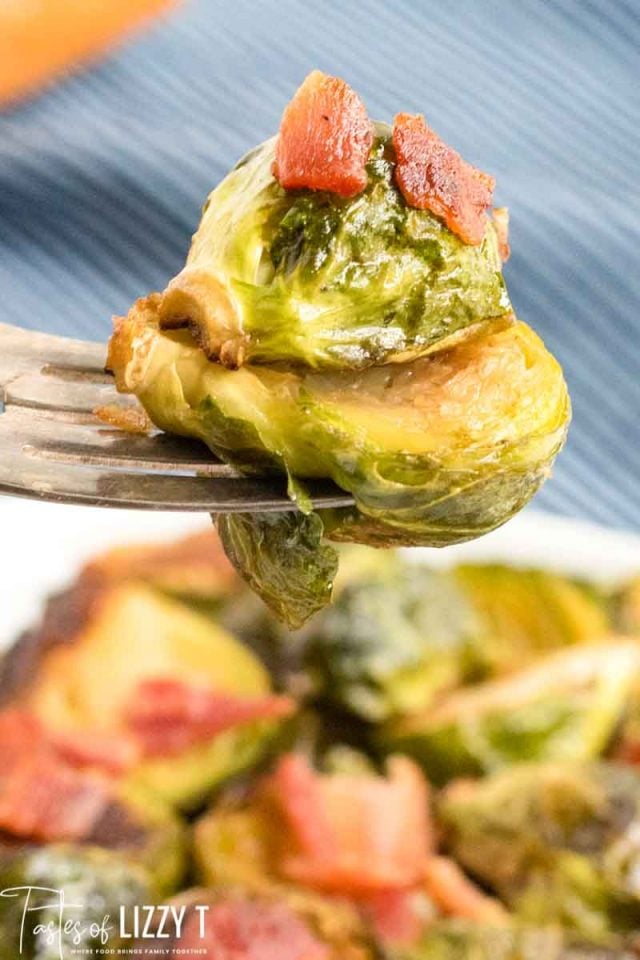 A close up of a plate of food, with Brussels sprouts on a fork