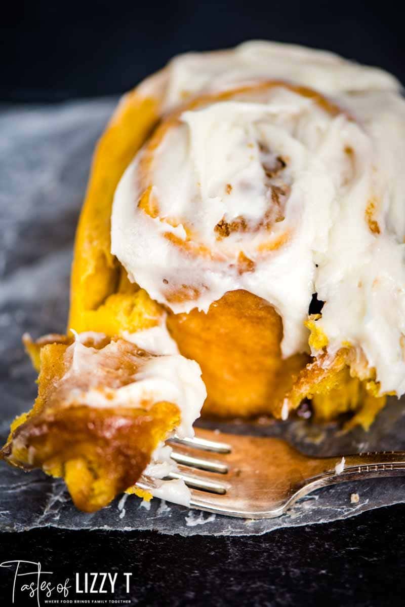 closeup of cinnamon roll and a fork with a bite