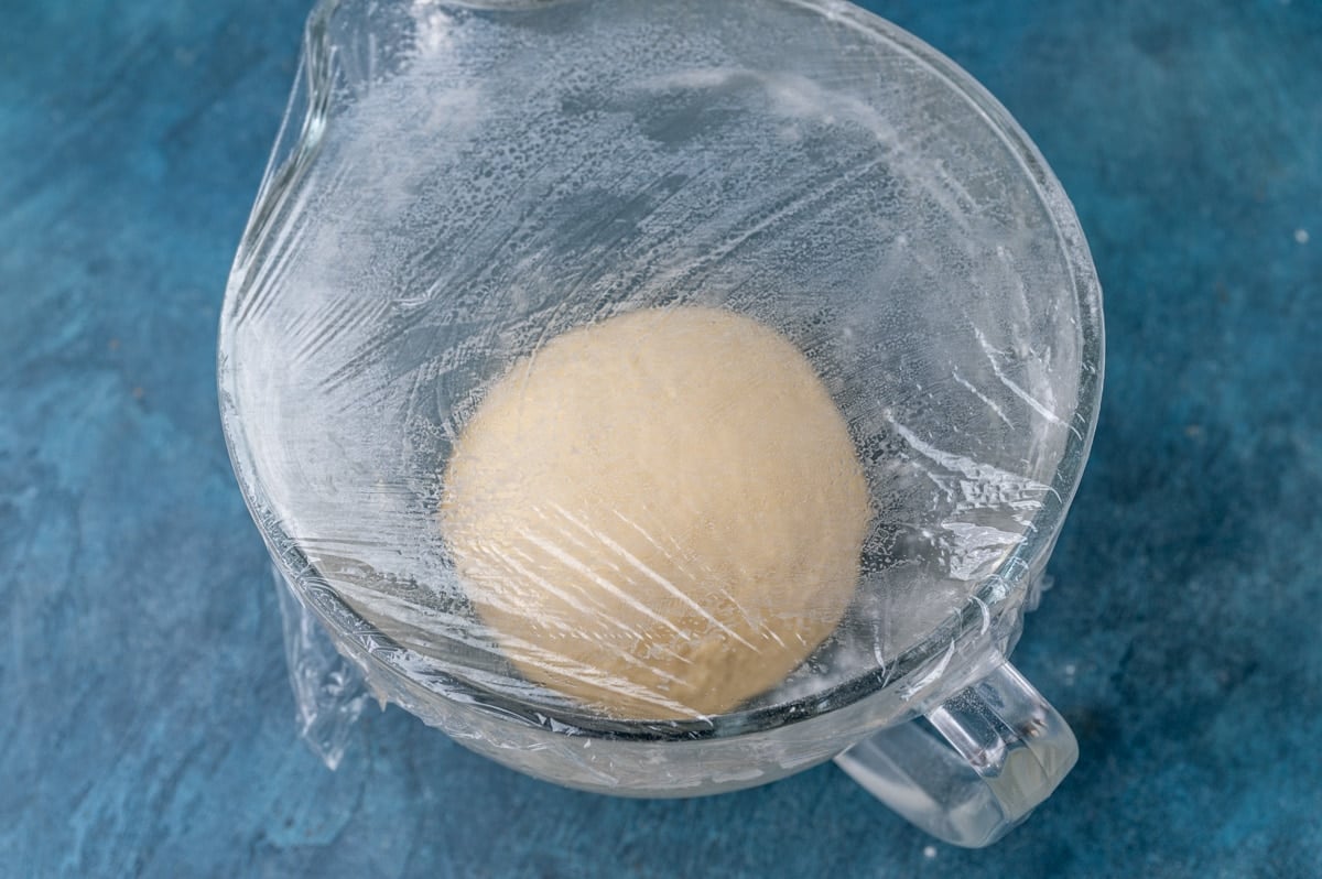 dough rising in a covered glass bowl