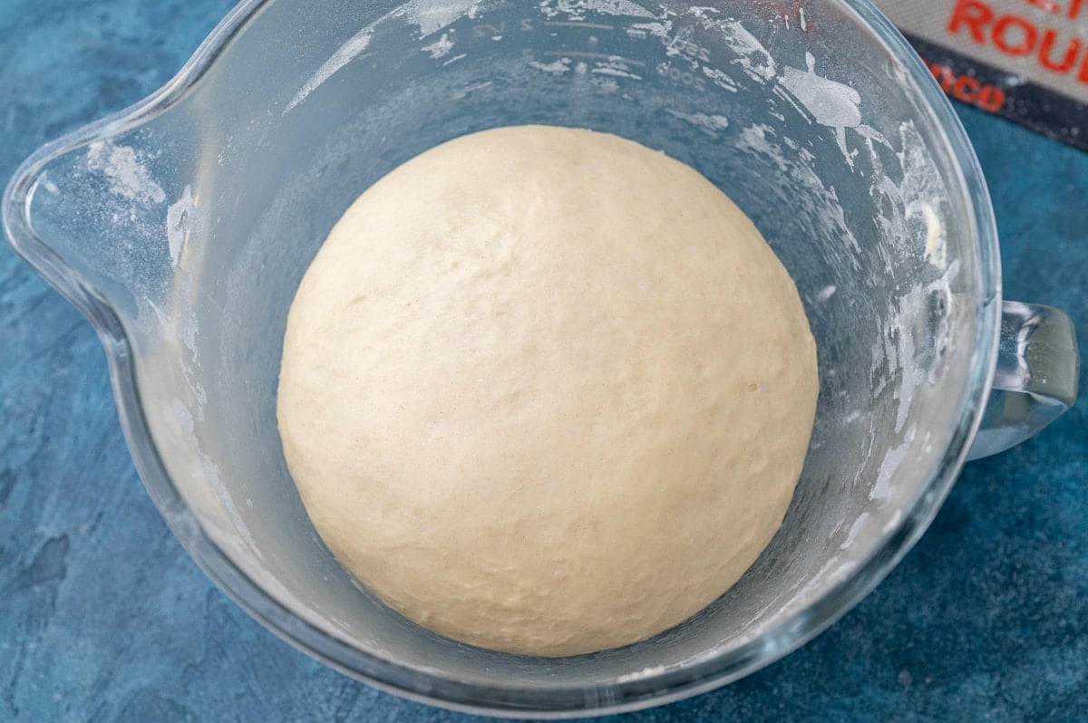 risen dough in a glass bowl