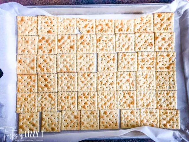 saltine crackers laid out on a baking sheet