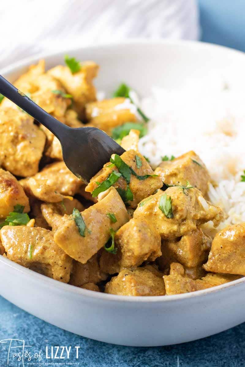 A bowl of food on a plate, with Curry and Chicken