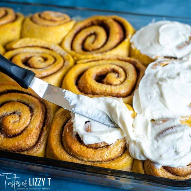 spreading frosting on cinnamon rolls