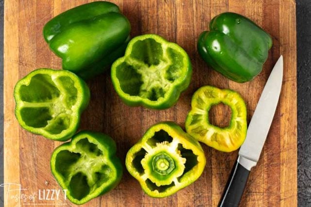 A green pepper on top of a wooden cutting board