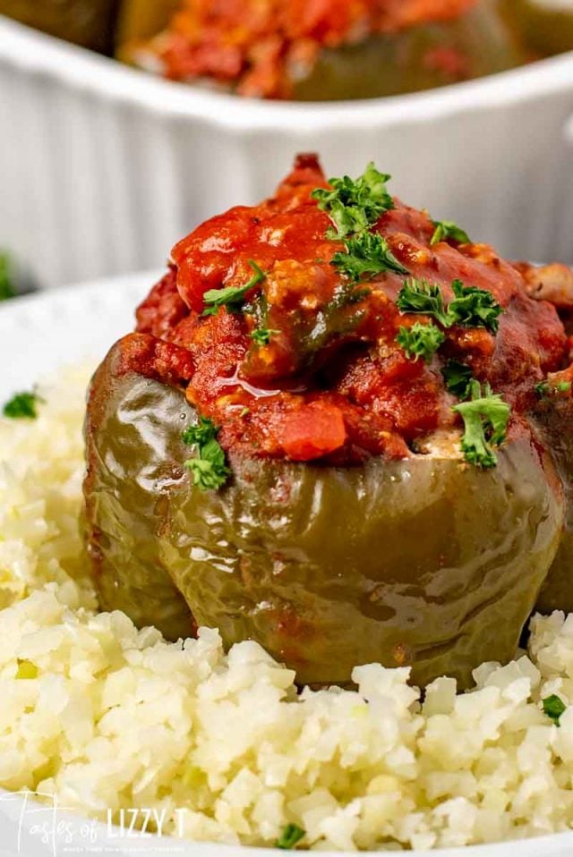 A close up of a plate of food with rice and vegetables, with Stuffed peppers