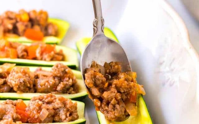 spoon filling halved zucchini