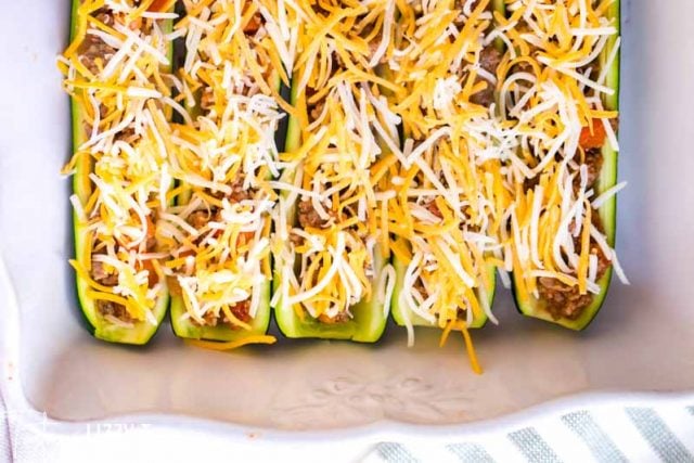 unbaked zucchini boats with shredded cheese on top