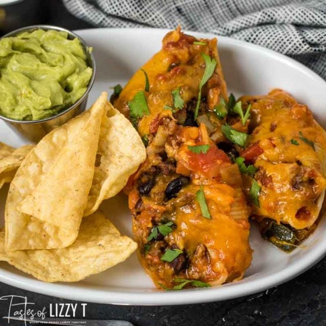 Taco Stuffed Shells on a plate with chips and guacamole