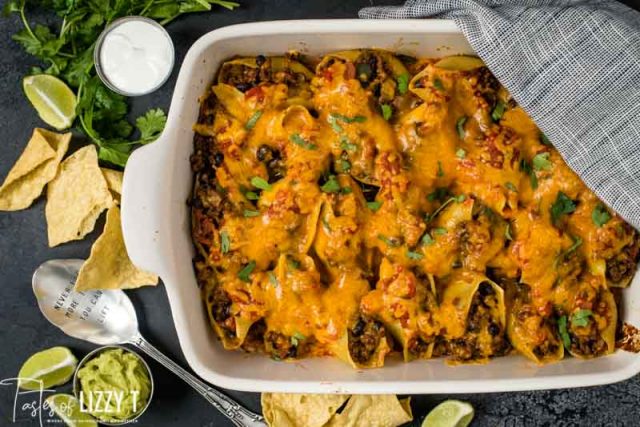 overhead shot of stuffed shells casserole with tortilla chips and garnishes