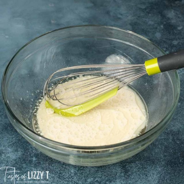 wet ingredients for sourdough bread in a bowl with a whisk