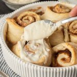 spreading frosting on cinnamon rolls