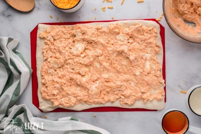 pizza dough rolled out with filling spread on top