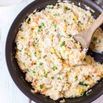Creamy Chicken and Rice in a skillet with a wooden spoon