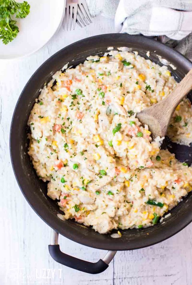 creamy chicken and rice in a skillet with wooden spoon
