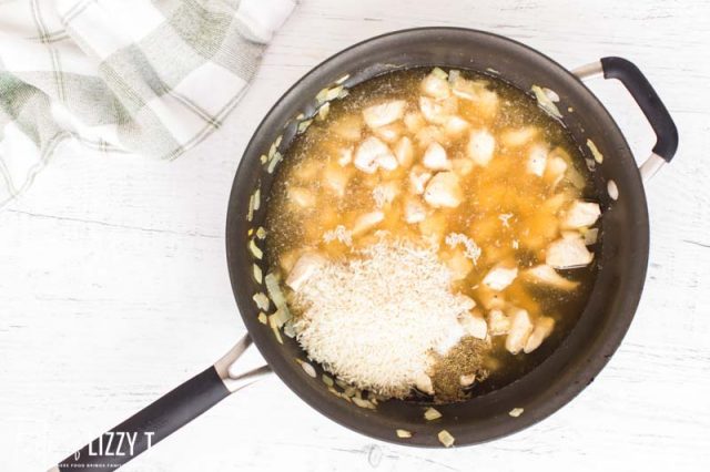 chicken broth, chicken and rice in a skillet