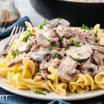 A bowl of pasta sits on a plate, with Beef