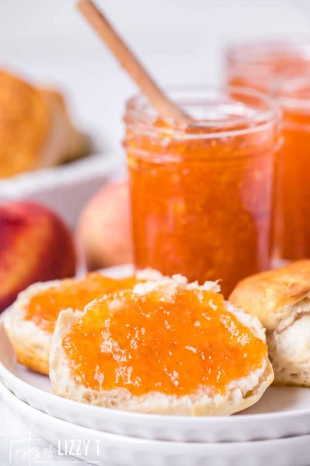 peach jam in a glass jar and biscuits with peach jam on a plate