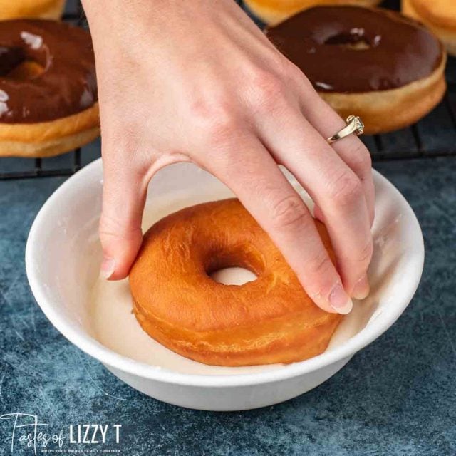 donut dipping in vanilla glaze