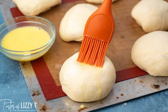 brushing egg wash on hamburger buns