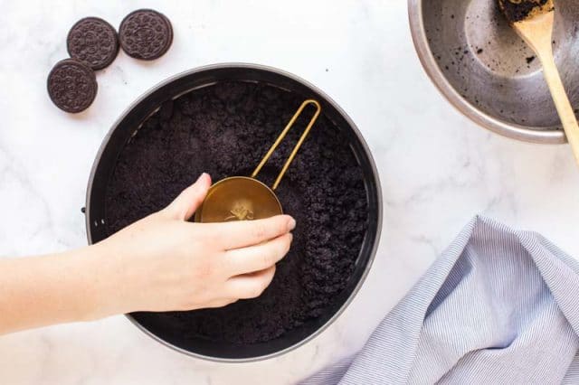 pressing an oreo crust into a springform pan