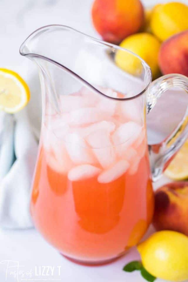 a pitcher of peach lemonade with ice