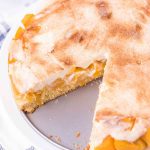 peaches and cream cake with a slice out of it