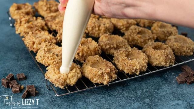 piping frosting into thumbprint cookies