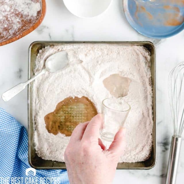 adding ingredients to pan for wacky cake