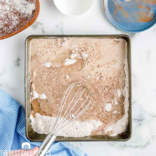 whisk mixing ingredients in 8x8 pan for crazy cake