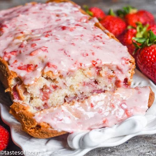 loaf of glazed strawberry bread with one slice cut