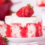 piece of strawberry jello poke cake with a strawberry on top