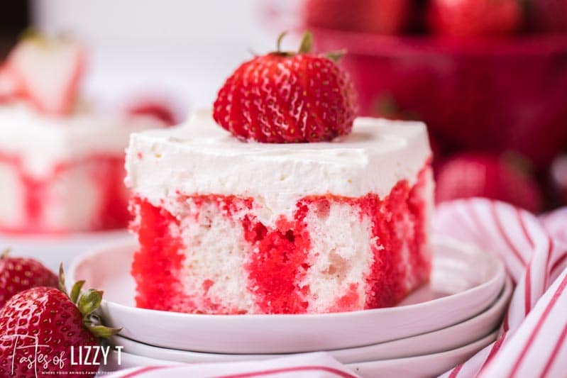 slice of jello poke cake with a strawberry on top on a white plate
