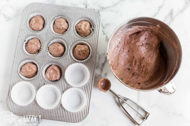 scooping cupcake batter into a pan