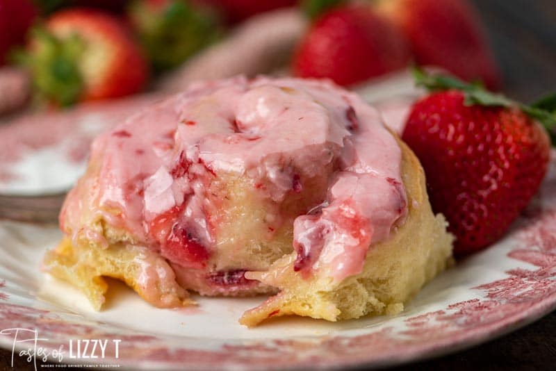 strawberries and cream sweet roll on a plate with a bite out of it